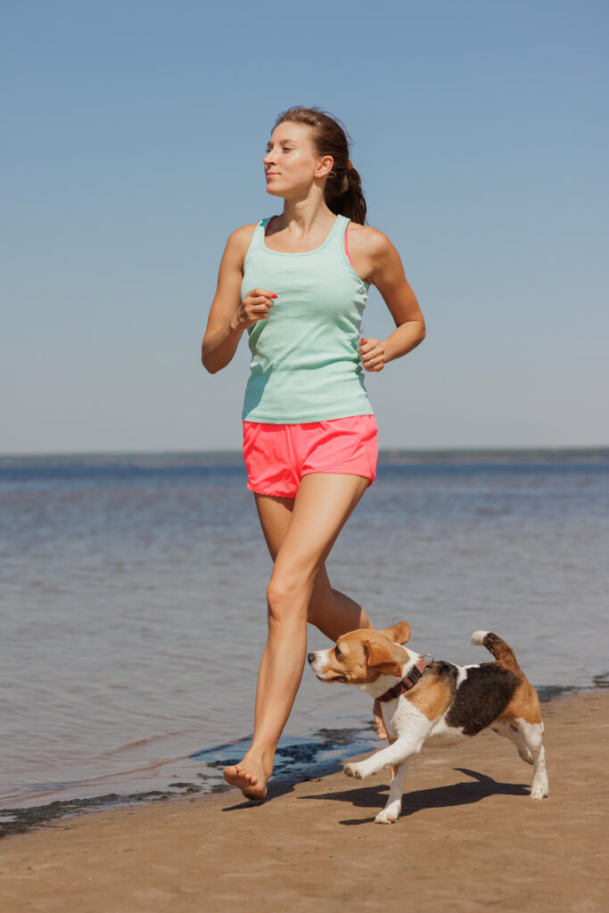 Hundesport - Frau Joggend mit Hund am-Strand-Northern-Dogs-Erziehung-und-Meer-Hundetraining-Rendsburg-Eckernförde